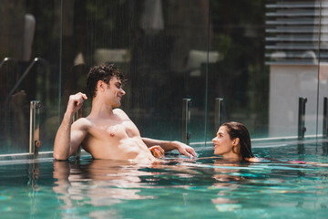 shirtless man looking at attractive woman in swimming pool