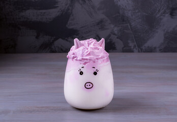 Piggy whipped milk topped with pink cream and marshmallow on the grey table