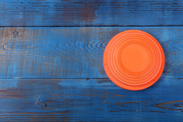 Orange flying target plate against the blue wooden background	