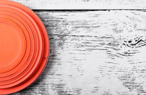 Orange flying target plate against white wooden background. Copy space