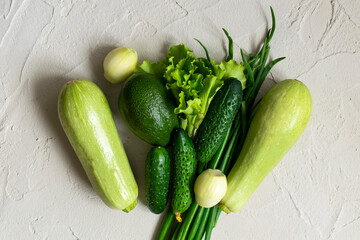 Assortment of fresh green organic vegetables on a concrete background.