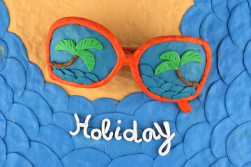 Sunglasses and sea coast made of plasticine, top view. Sunglasses with reflection of sea and palms.  Holiday concept. Sea, sand and beach concept..