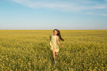 Fototapeta premium portrait of a teenage girl in a yellow dress running across the field in summer