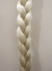 Close up detail of blond braid selected on light grey background