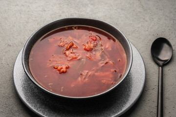 Vegetarian borscht in a concrete plate on a concrete post near the black spoon