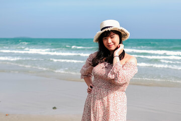 Young Asian woman in a cute dress is relaxing at the beach.