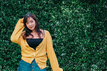 Close up of young pretty Asian woman in blue yellow sweater with garden background.