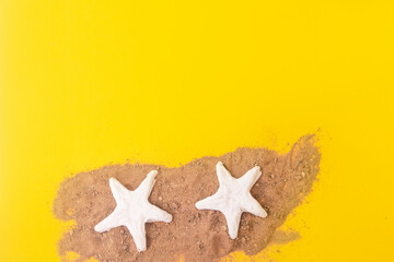 Fototapeta na wymiar starfish on the sand on a yellow background. Concept of travel or vacation holidays.