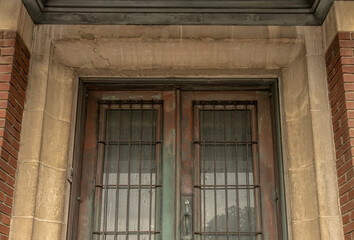 Tarnished Art Deco copper doors  and windows with metal  bars in stone doorway of heritage electrical substation