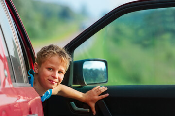 happy boy travel by car in summer nature