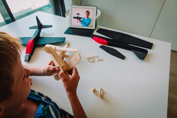 boy making model of plane with online video lesson, kids engineering