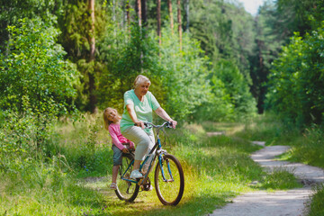 happy little girl with grandmother on bike ride in nature