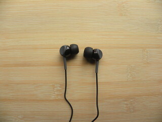 Black color in-ear headphones on wooden table
