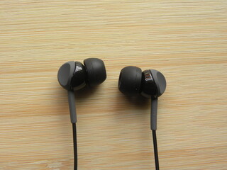 Black color in-ear headphones on wooden table