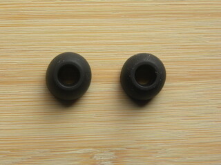 Pair of black earphone pads of in-ear earphones kept on wooden table