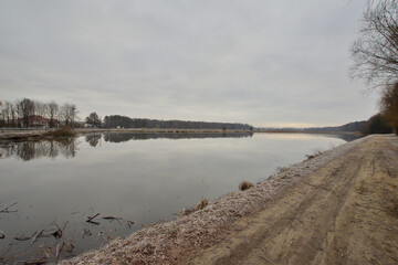The causeway separates the bank of the pond from the river on a gloomy morning on an autumn cold day.