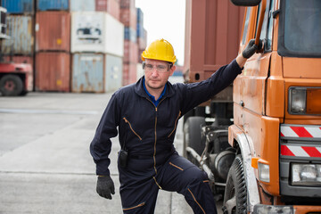 Young truck driver at yard port with delivery truck in container warehouse.