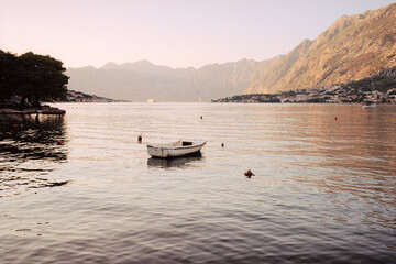 Fototapeta na wymiar View of the fishing boat in the Bay of Kotor in Montenegro at sunset. Real grain scanned film.