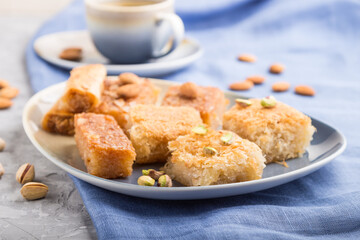 traditional arabic sweets and a cup of coffee on a gray concrete background. side view, selective focus.