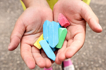 The child's hands hold colorful crayons, close-up, top view-the concept of exciting outdoor activities