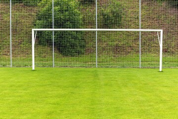 Empty football or soccer white gates. Soccer gate on green grassy field on a country playground.