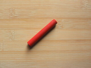 Red oil pastel stick kept on wooden table
