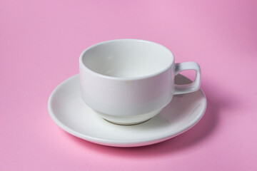 White cup on a pink background. Empty white porcelain cup on a saucer.