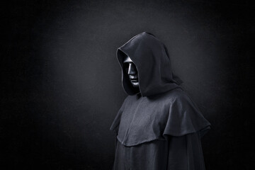 Scary figure in hooded cloak in the dark
