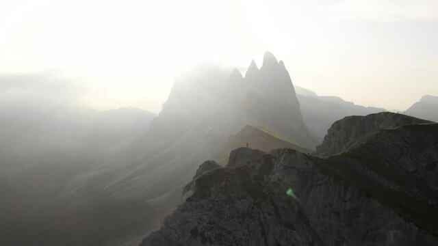 Drone circle around man hiker staning on Seceda peak, Dolomites Italy. Aerial view of Geisler mountain group in South Tirol, European Alps travel destinations