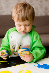 Very serious face. Toddler painting with sponge and hands.