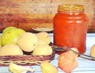 Food still life with apricots, a pear and a pot of handmade apricot jam. Healthy breakfast. Summer fruits and vitamins.  