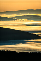 Obraz premium A hazy sunrise in the mountains. Mountains silhouettes and fog in the valleys. Photo from Polonina Wetlinska. Bieszczady National Park. Carpathians. Poland.
