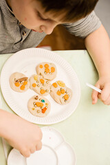 Kid decorating play dough pancakes.