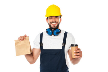 Handsome workman holding coffee to go and paper bag and smiling at camera isolated on white