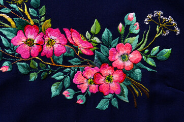 Beautiful pink flowers embroidered on dark fabric. Ukrainian folk embroidery. Fabric decor.