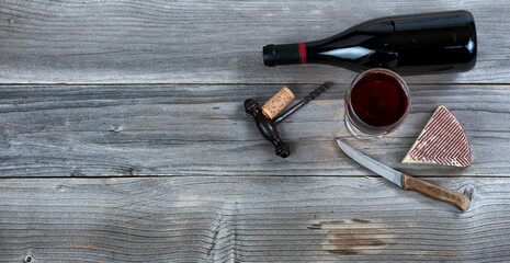 Cheese wedge and red wine in a glass on rustic wood