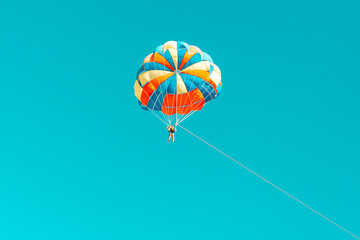 Parachute parasailing of tourists on a sandy beach Sunny weather against the background of clear sea and ocean.The wind blows up the canopy of the parachute against a clear blue sky with clouds