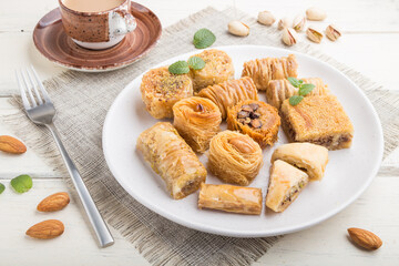 traditional arabic sweets (kunafa, baklava)  and a cup of coffee on a white wooden background. side view.