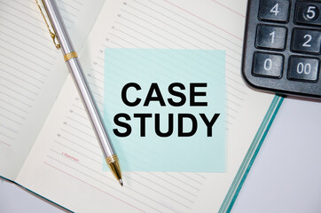 The word case study is written on a paper blue block near a calculator and notepad. pen next