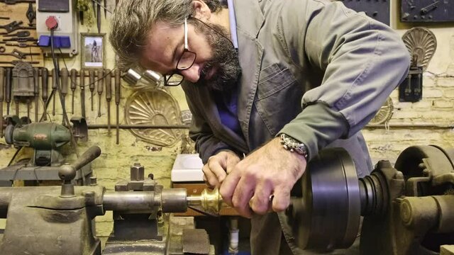 Crop concentrated goldsmith using sharpening machine in workshop