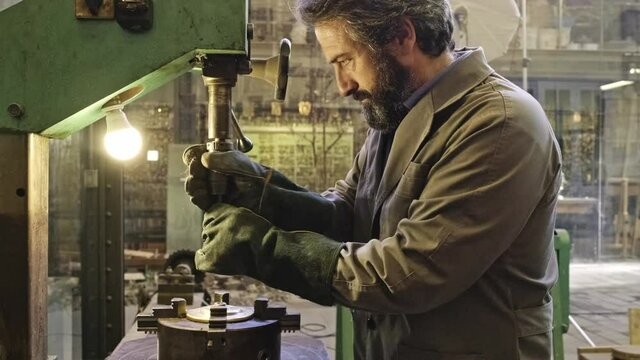 Mature jeweler working on engraving machine in workshop