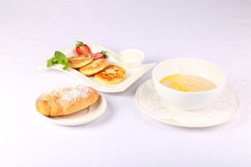 Cheesecakes, oatmeal and croissant on white background