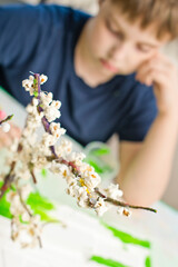 Spring theme. Boy making flowering apple tree garden layout. Recycling concept. Trees made of tree branch and styrofoam.