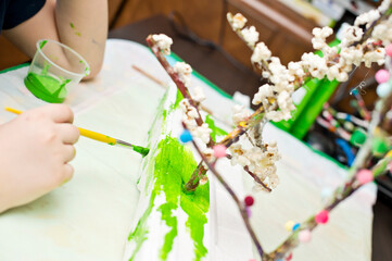 Spring theme. Boy making flowering apple tree garden layout. Recycling concept. Trees made of tree branch and styrofoam.