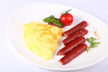 Omelet with sausage and arugula on a white wooden background