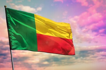 Fluttering Benin flag on colorful cloudy sky background. Prosperity concept.