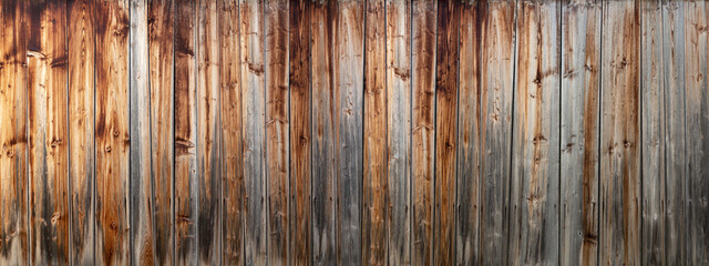 Panorama Detail einer alten, verwitterten, grau braunen Holzwand aus vertikalen Brettern