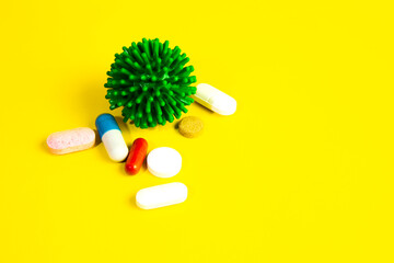 COVID-19 on a yellow background. New coronavirus infection. Image of a green coronavirus. Tablets, antibiotics against the disease of pneumonia and cough.