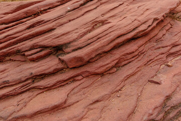 Sandstone forms when layers of sand accumulates by sedimentation are compacted & cemented by precipitation of minerals within pore spaces of sand grains. Red color is imparted by Hematite Iron oxide.
