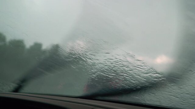 Driver driving on highway in bad rain storm with windshield wipers on high speed. 